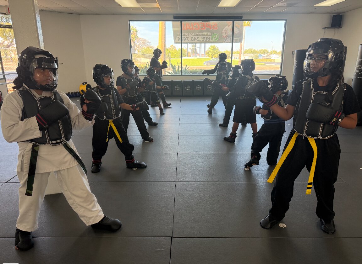 Students in full sparring gear working drills with a coach